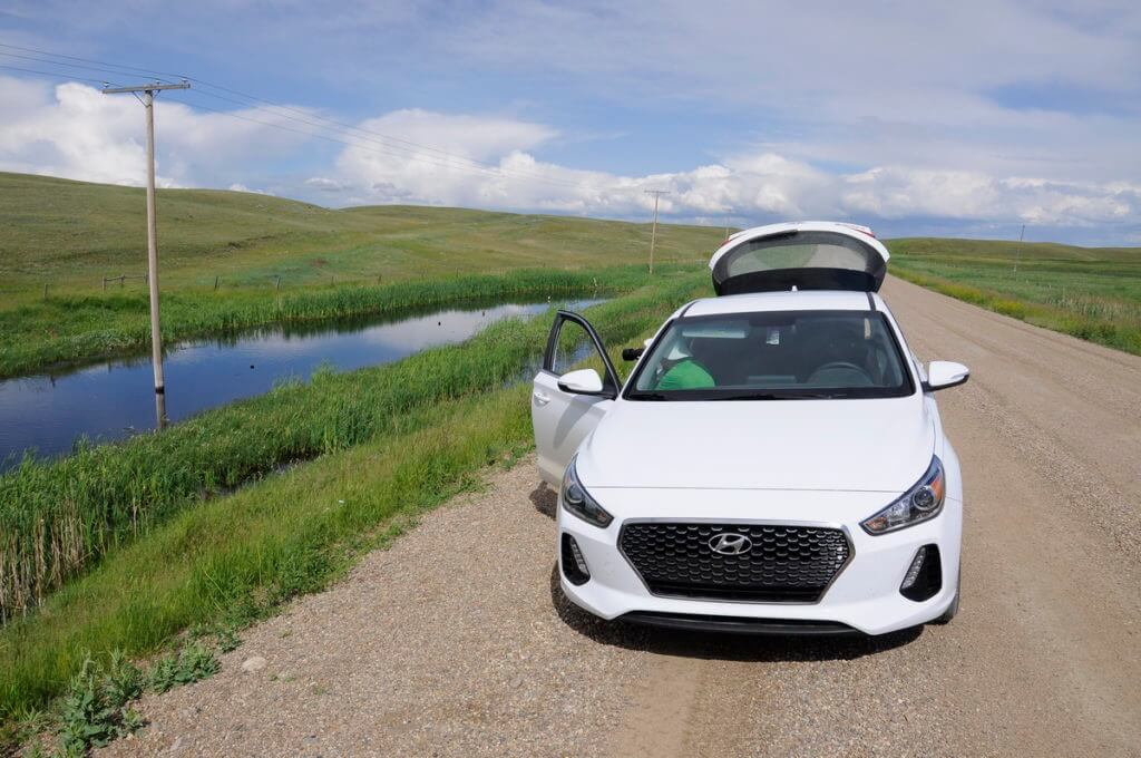 Image of a car parked beside a vernal pool, val marie, saskatchewan