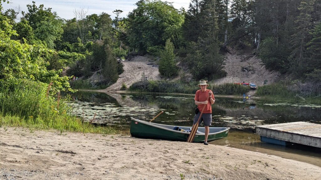 image of bob with his canoe on the outlet river in sandbanks provincial park, ontario
