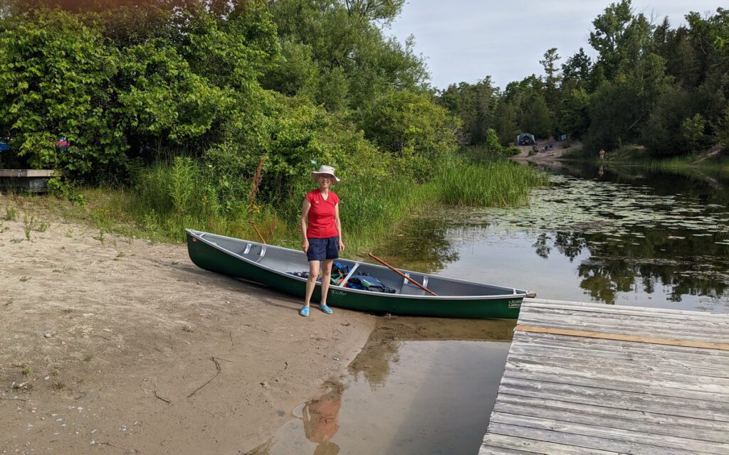 image of jean with the canoe on the outlet river in sandbanks provincial park, ontario