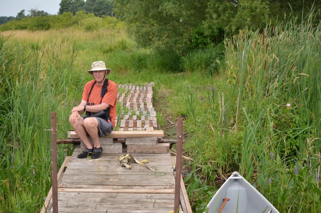image of bob sitting on a dock along east lake, sandbanks provincial park, ontario