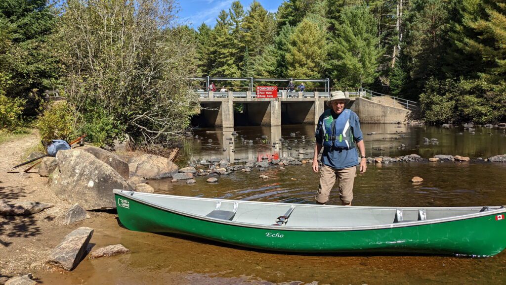 Image of Bob putting canoe on to the river in Algonquin Park.