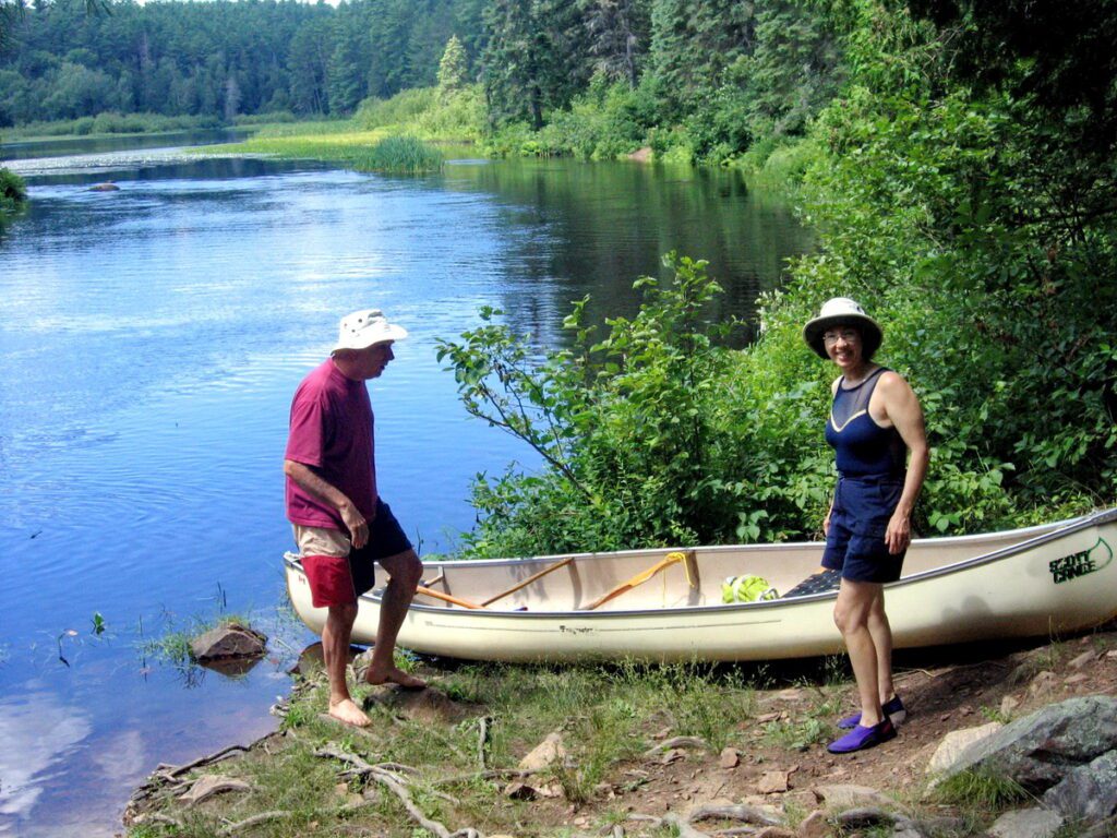 Image of Bob and Jean putting their canyon into the Barron Canyon River in Algonquin Park, Ontario, Canada. A popular canoeing route..