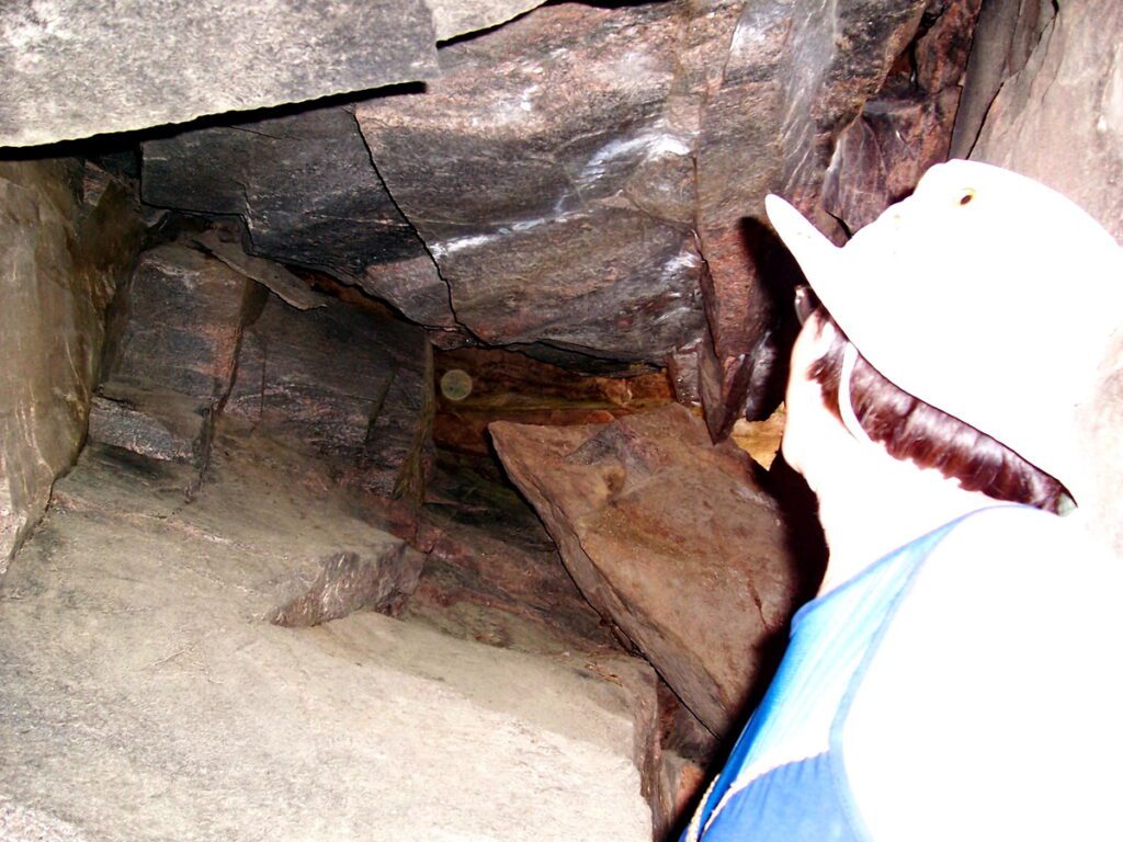 Image of Jean inspecting a cave along Barron Canyon in Algonquin Park, Ontario, Canada. A popular canoeing route..
