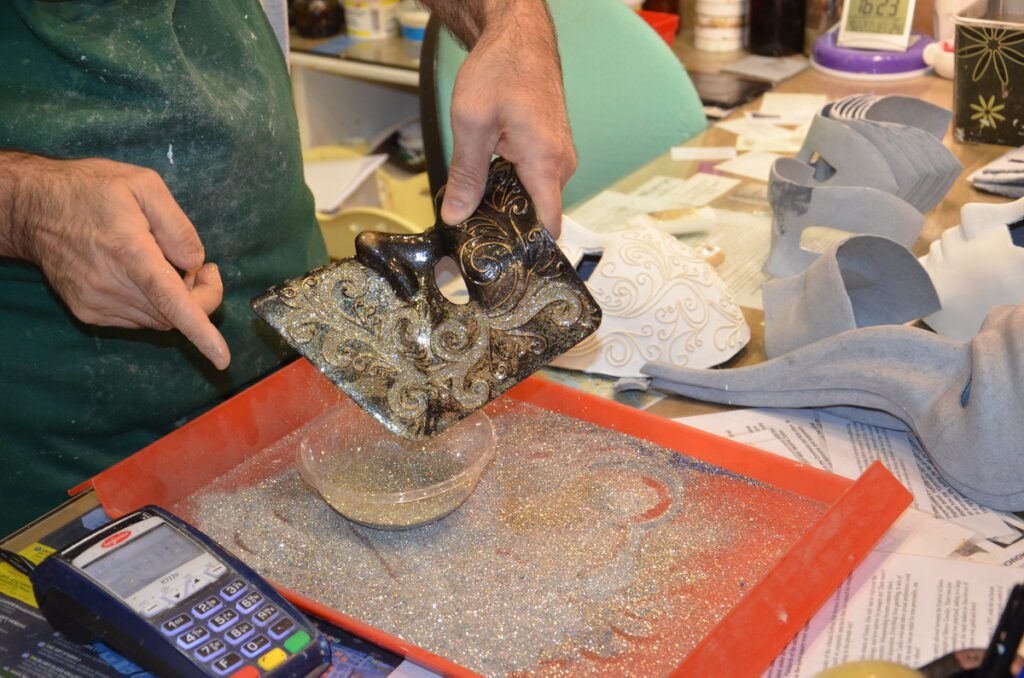 image of glitter being applied to a bauta mask, venice, italy