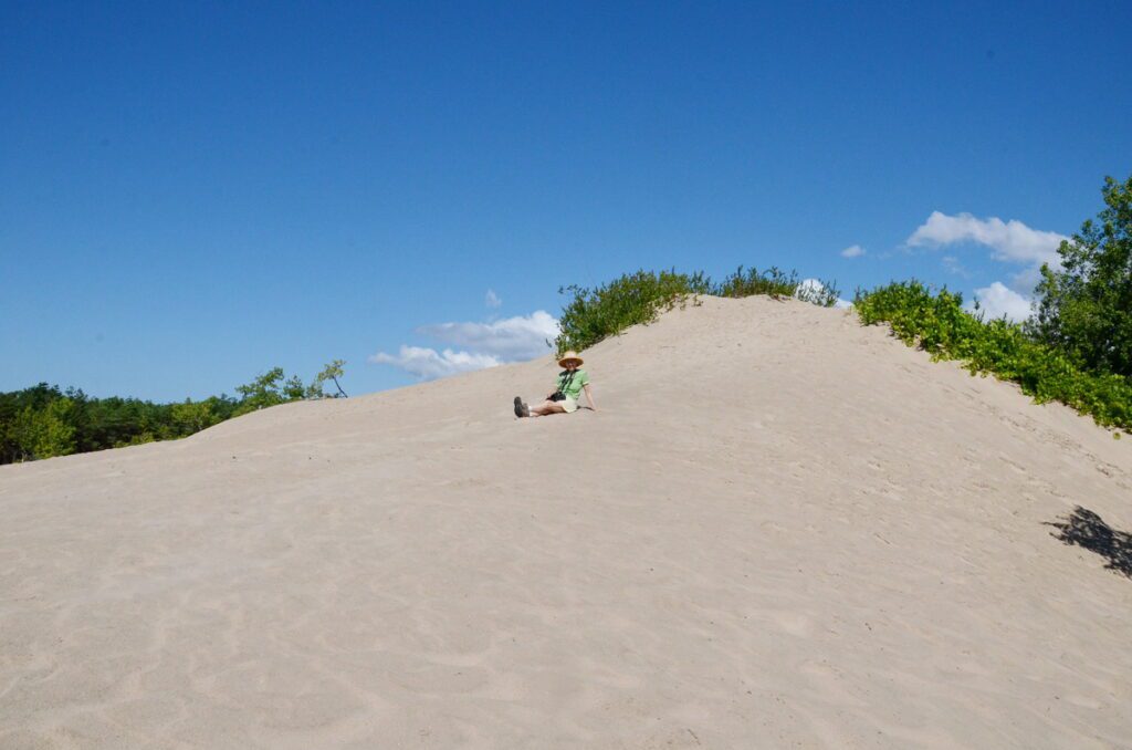 image of jean sitting on a sand dune, sandbanks provincial park, ontario