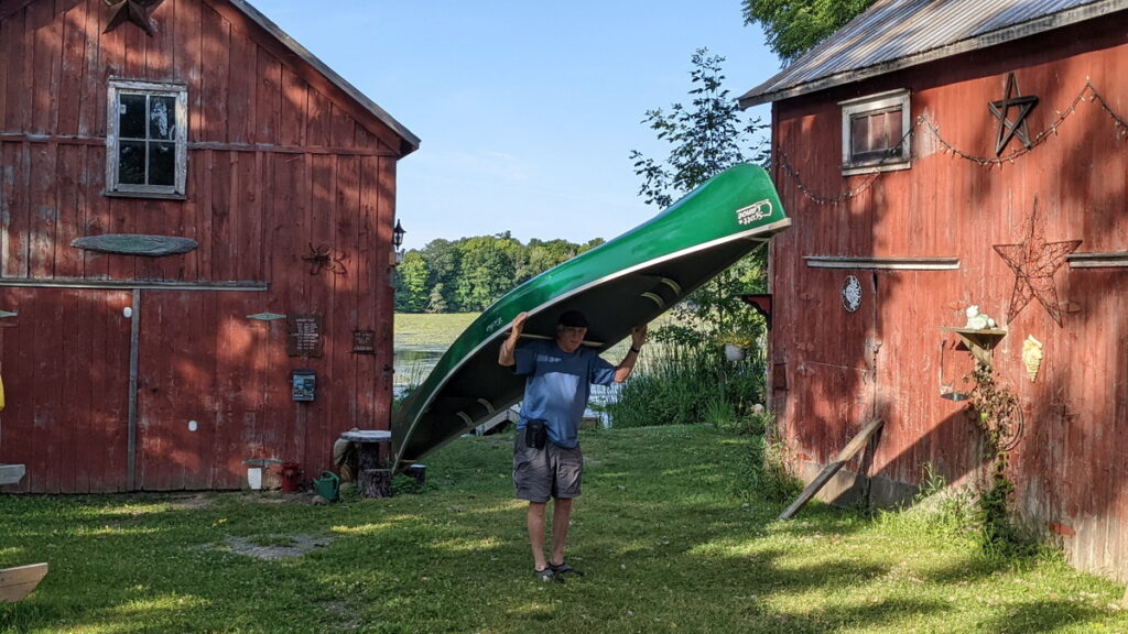 image of bob carrying our canoe, cabin fever kayak, black river, prince edward county, ontario