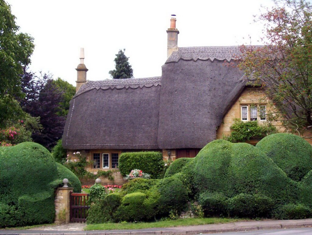 image of a thatched cottage and manicured hedge, chipping campden, england