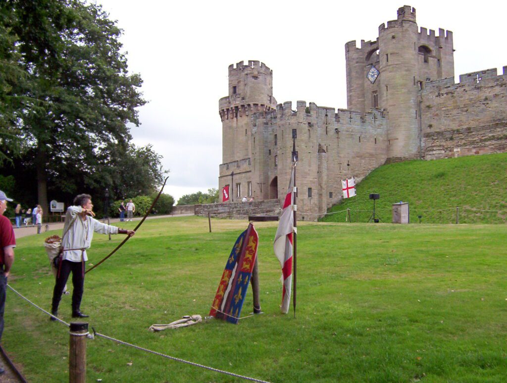 image of actors in period costume performing archery, warwick castle, england