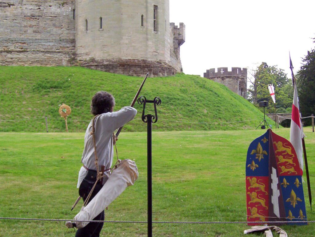 image of actors in period costume performing archery, warwick castle, england