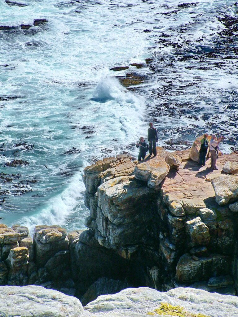 image of tourists on rocky promontory at cape point, cape of good hope nature reserve, south africa