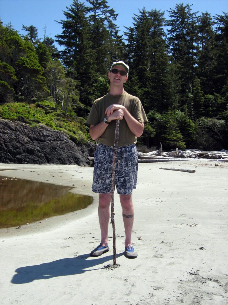 image of a man with a walking stick on the beach, ahous bay, vargas island, british columbia