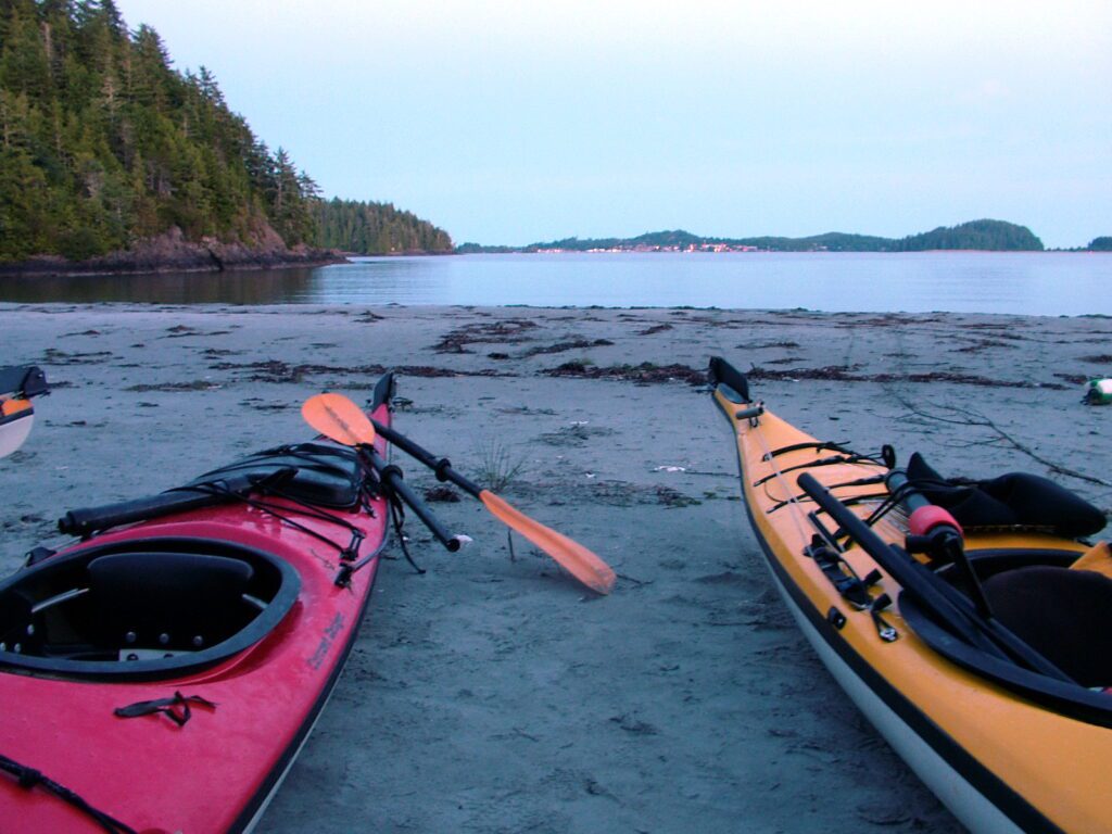 image of kayaks and a view back towards tofino, vargas island, british columbia