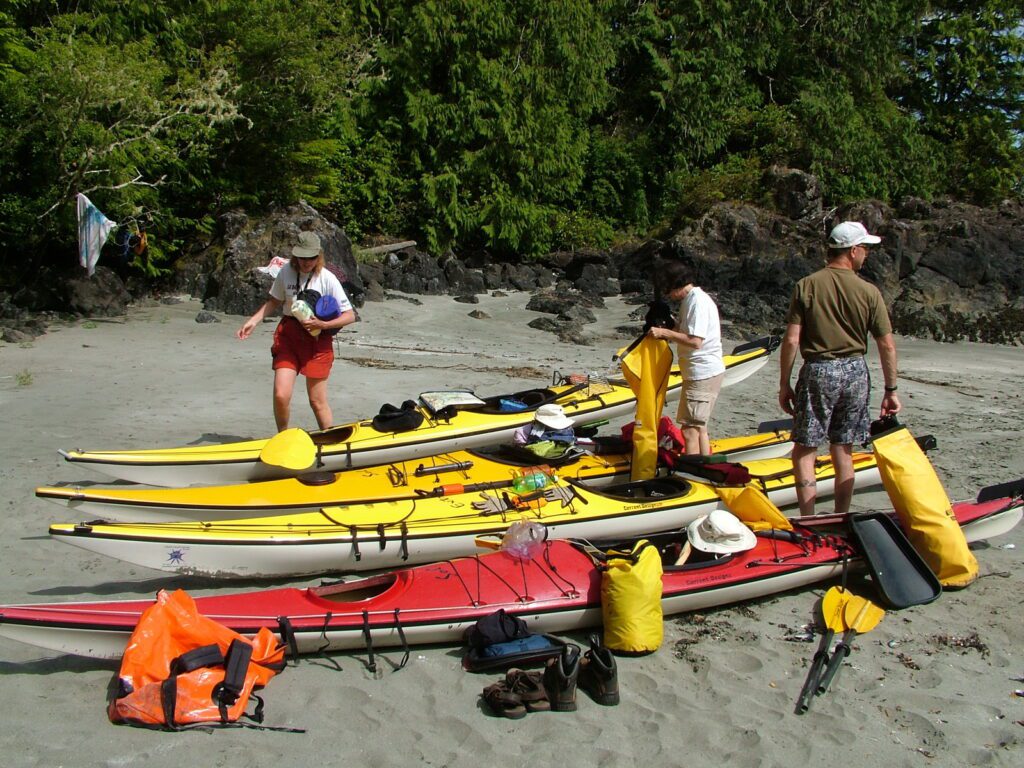image of people and kayaks on a sandy beach, ahous bay, vargas island, british columbia 