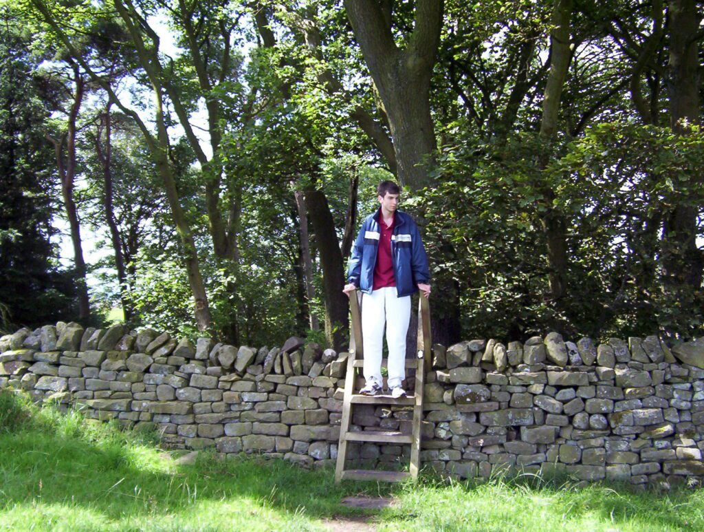 image of a person using a stile to cross Hadrian's Wall, England