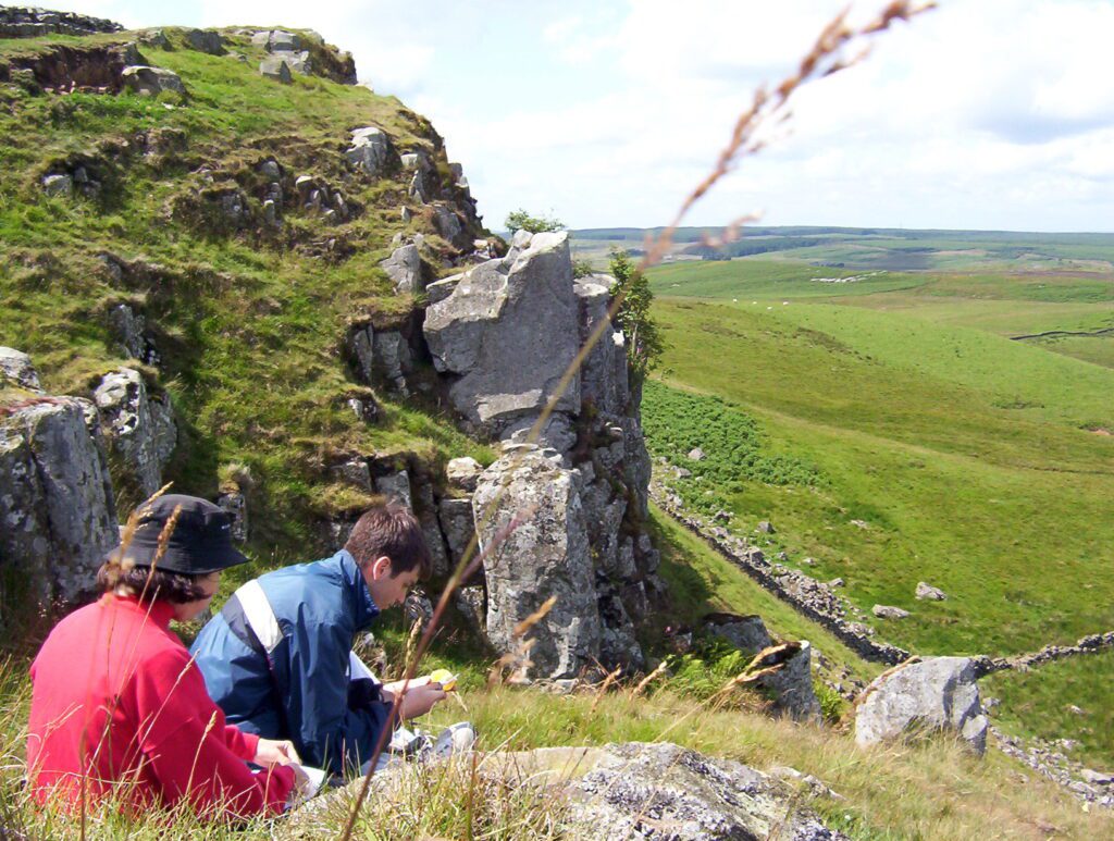 image of people resting on the grass below Sewingshields Milecastle 35, Hadrian's Wall, England