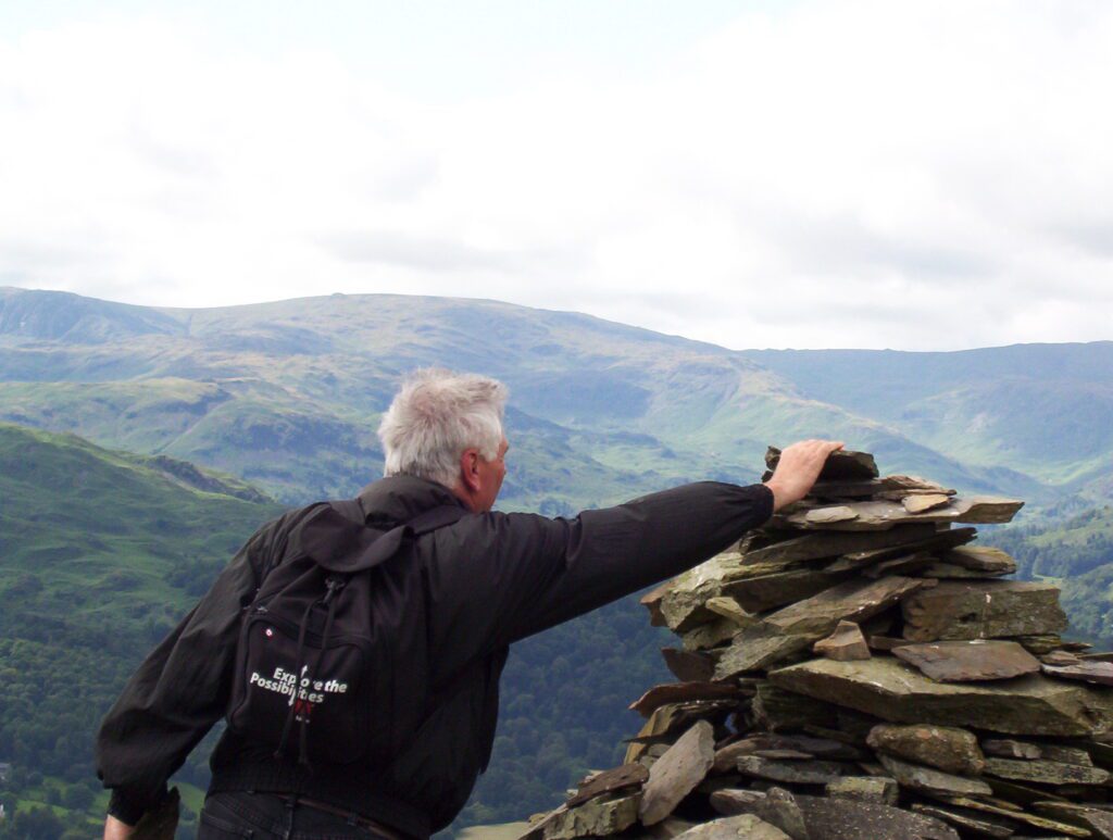 image of bob placing a rock on the cairn, wansfell pike, lake district national park, ambleside, England